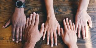 Ein diverses Team ist durch ganz unterschiedlich aussehende Arme dargestellt; Foto: Unsplash, Clay Banks
